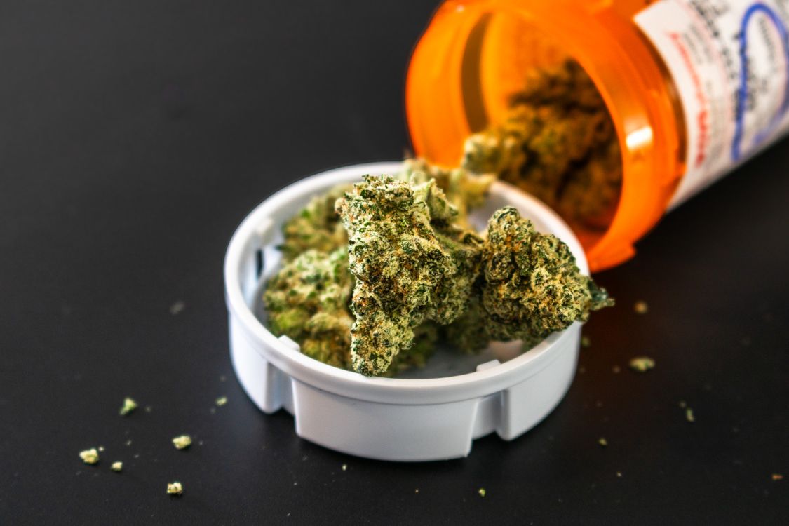Cannabis flower buds in a glass apothecary jar representing the medical and recreational effects of THC and CBD
