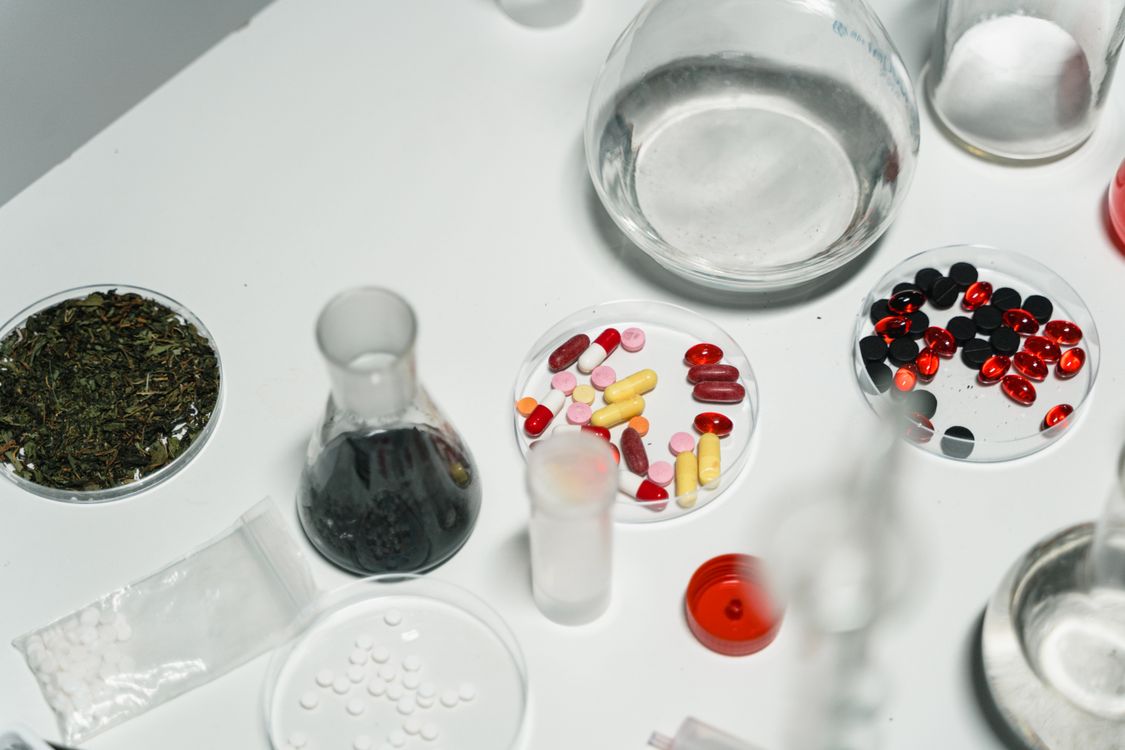 White prescription pills and cannabis flower buds on white marble, representing the interaction between cannabis and antidepressants