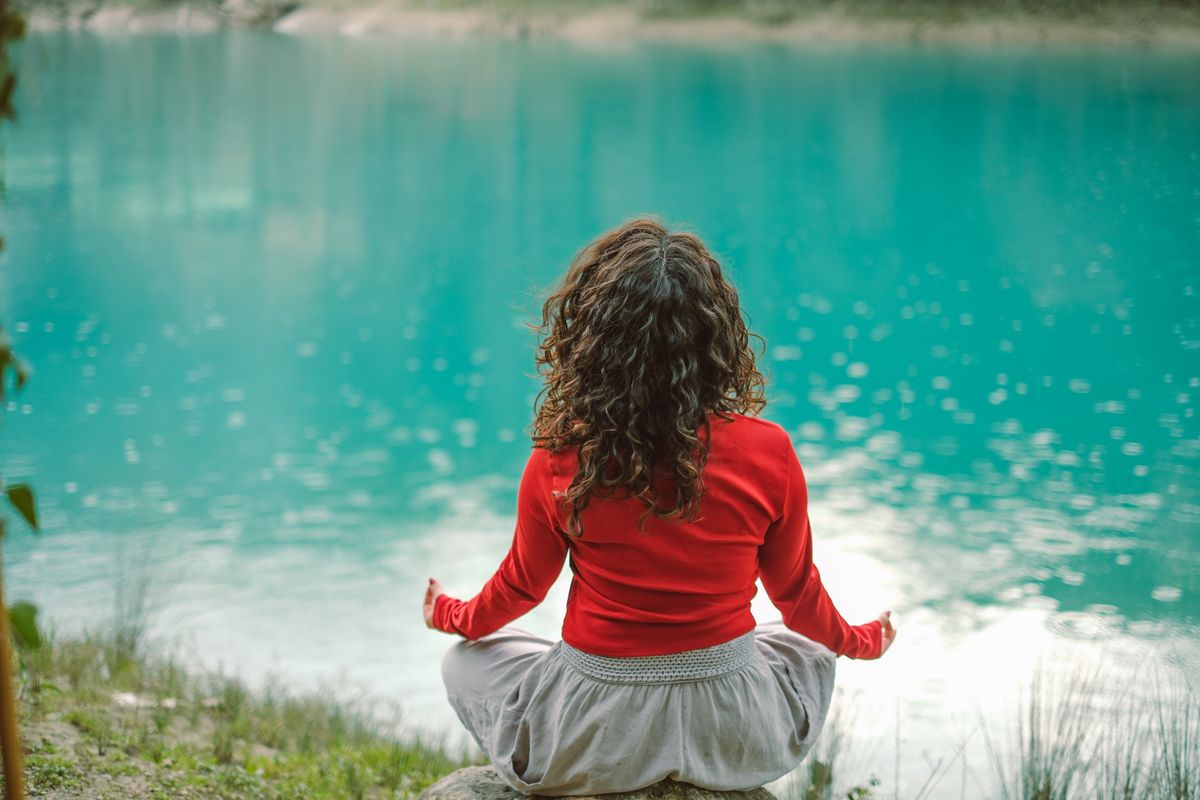 Woman meditating by water in nature representing cannabis for anxiety relief in Australia