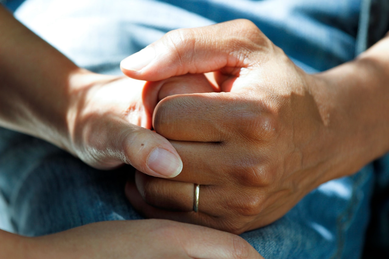 Two people clasping hands in a hospital setting representing support and care for cancer patients using medicinal cannabis in Australia