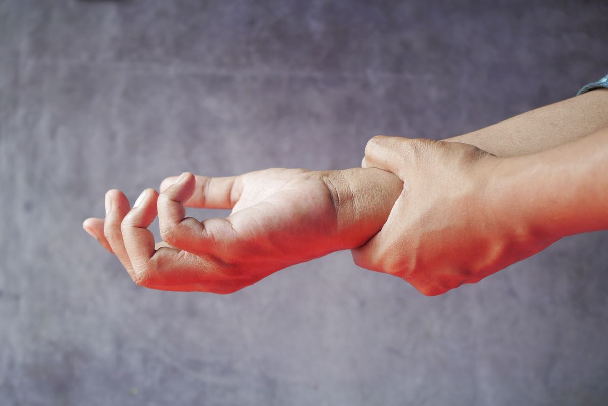 Person holding their hand gently representing chronic pain and cannabis-based pain relief in Australia