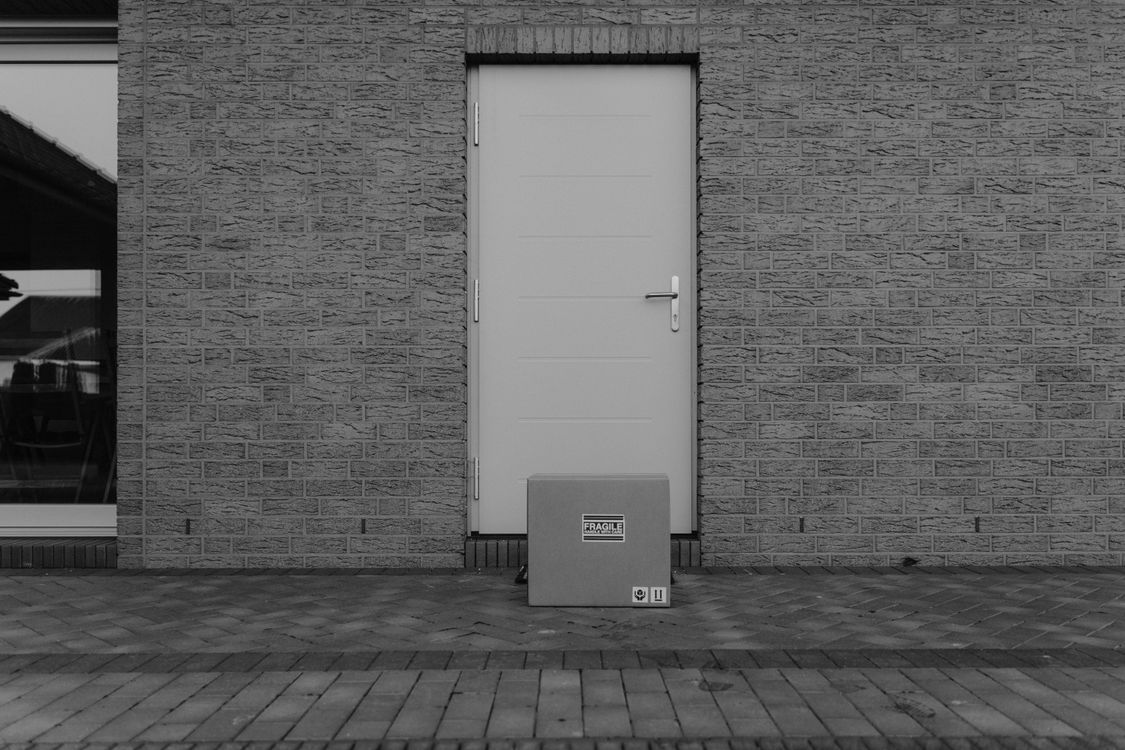 Courier handing a discreet plain delivery package to a customer at an Australian front door
